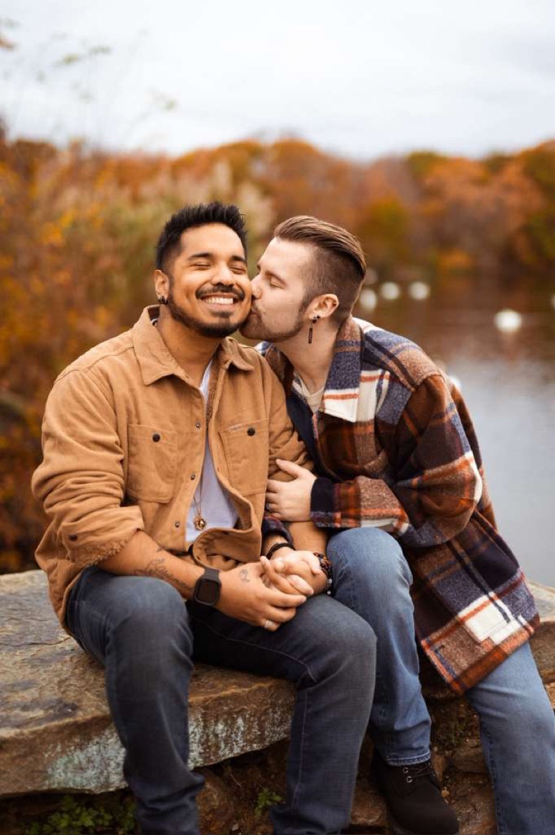 Frankie kissing Rodrigo by an autumn lake